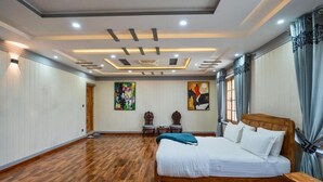 Un dormitorio amplio con una cama grande, suelo de madera y un diseño de techo moderno.