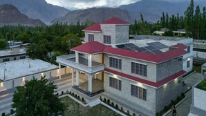 Un edificio de varios pisos con techo rojo, paneles solares y un balcón.