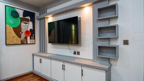 Una cocina moderna con armarios blancos, televisor integrado y piso de madera.
