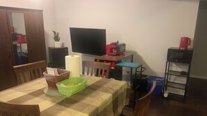 A dining area with a checkered tablecloth, wooden chairs, a television, a red appliance, and a small shelf with a red mug. - Cozy Luxury in peaceful Caledonia,  13 minutes away from Hamilton Airport  (Caledonia)