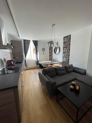 Ein moderner Wohnbereich mit Küche, Essbereich und einem großen grauen Sofa.
