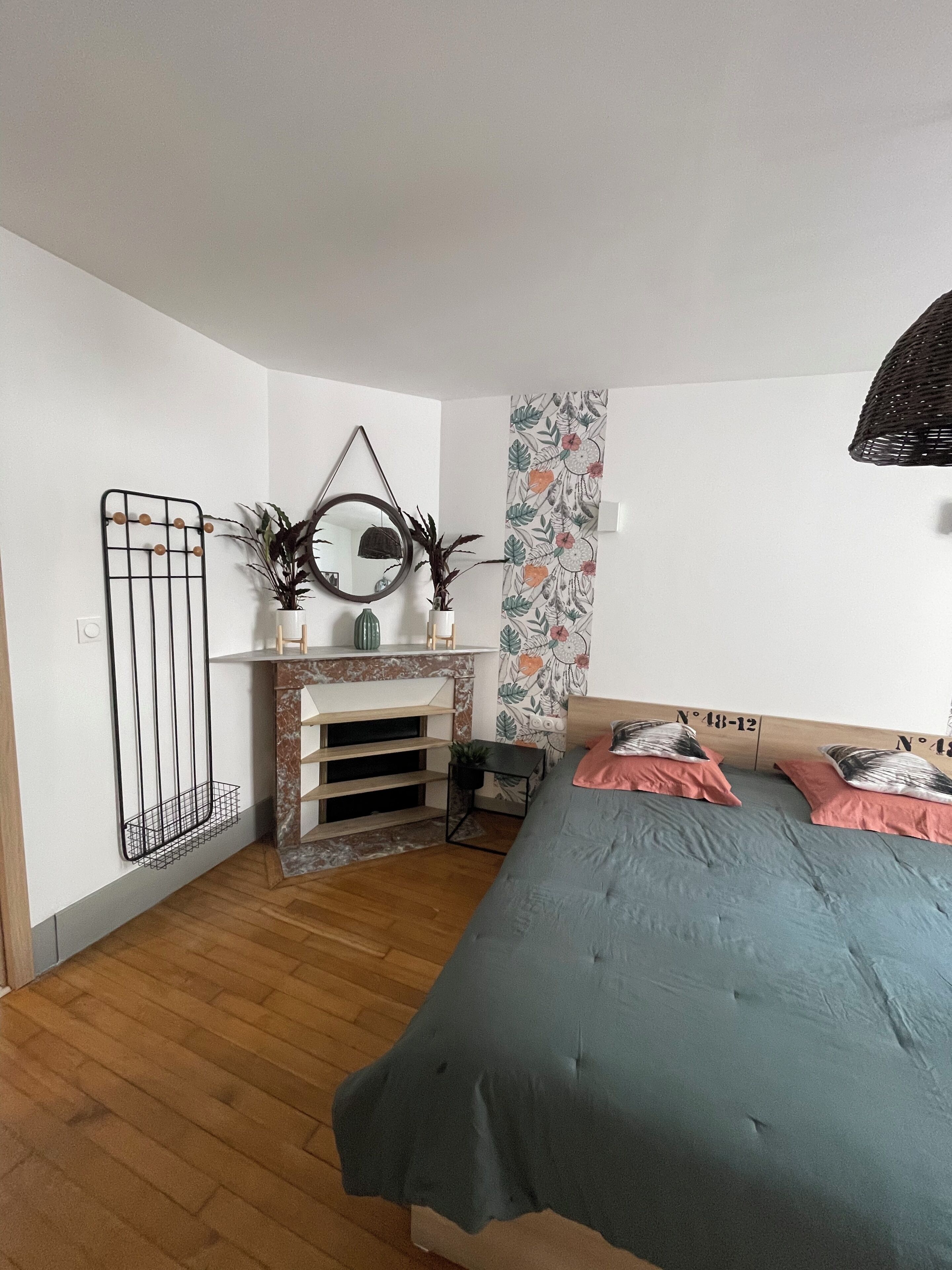 Un dormitorio con cama, un escritorio pequeño, un espejo y un radiador fijado a la pared.