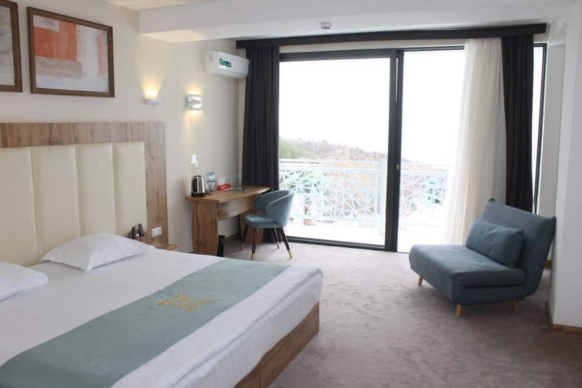 Une chambre d’hôtel avec un lit, un bureau, une chaise et un balcon offrant une vue.