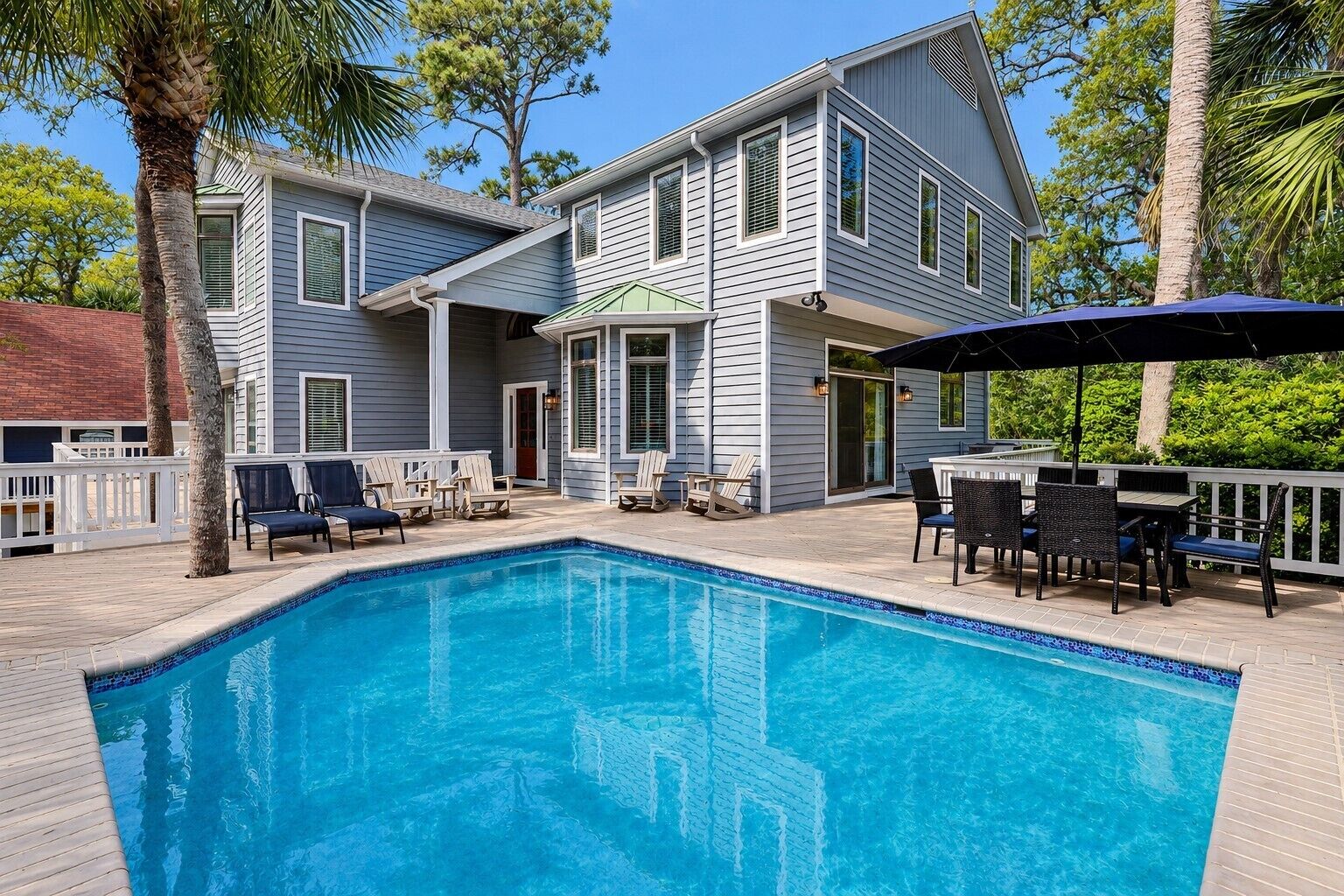 Ein zweistöckiges Haus mit Swimmingpool, Gartenmöbeln und einer überdachten Terrasse.