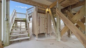Een houten constructie met een trap die leidt naar een terras, omgeven door een zandstrand.