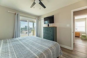Ein Schlafzimmer mit Bett, Fernseher, Kommode und Balkon.
