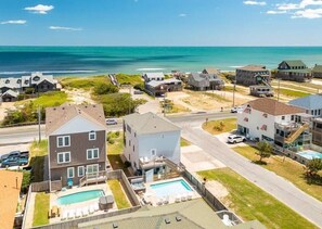 Ein Küstenwohngebiet mit Häusern, einem Swimmingpool und einem Strand im Hintergrund.