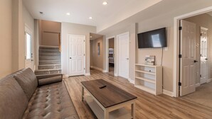 Un salon comprenant un canapé, une table basse, un téléviseur et un escalier menant à une autre pièce.