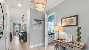 Una cocina moderna con una isla central, un comedor con taburetes de bar y un pasillo que conduce a un baño.