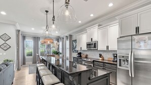 Una cocina moderna con una isla central, electrodomésticos de acero inoxidable e iluminación colgante.