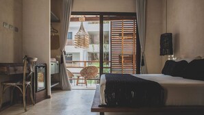 A bedroom with a bed, a desk, and a chair. There is a window with curtains and a view of greenery outside. - Cozy Rooms to let (Tulum)