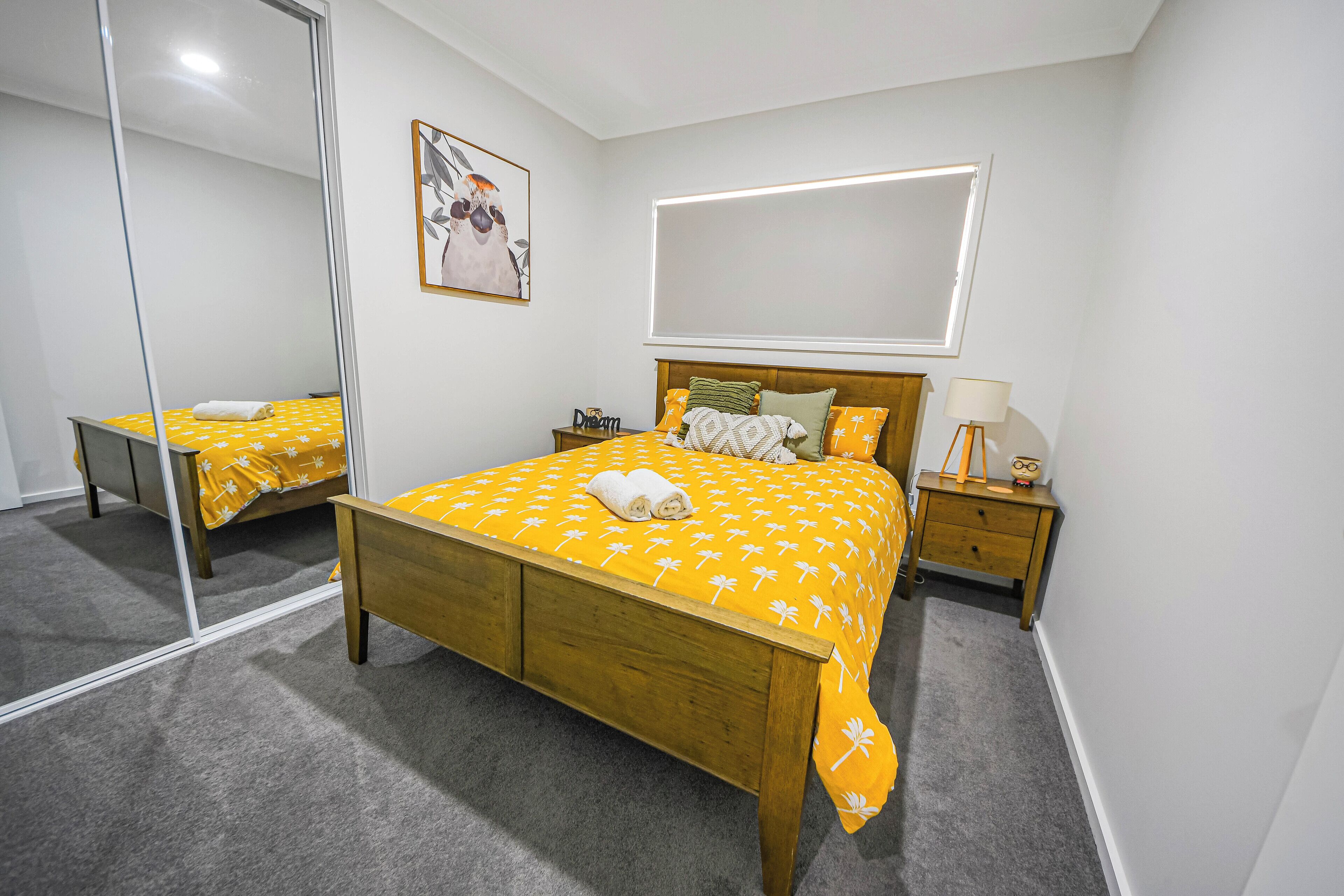 Una camera da letto con un letto di legno, un comodino, uno specchio e un quadro appeso al muro.