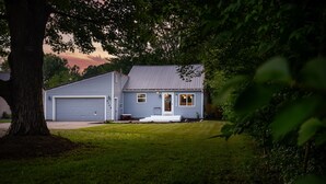 Ein eingeschossiges Haus mit Garage, einer Veranda und einem Baum im Vordergrund.