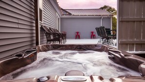 Ein Whirlpool mit Bedienfeld, umgeben von Gartenmöbeln und einer überdachten Terrasse.