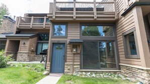 A two-story house with a balcony, a stone foundation, and a front door. - Cedars Liftside Townhome: Ski In/Ski Out (Breckenridge)