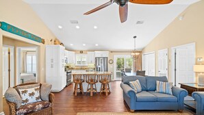 A spacious living area with a blue sofa, wicker chair, and a ceiling fan.