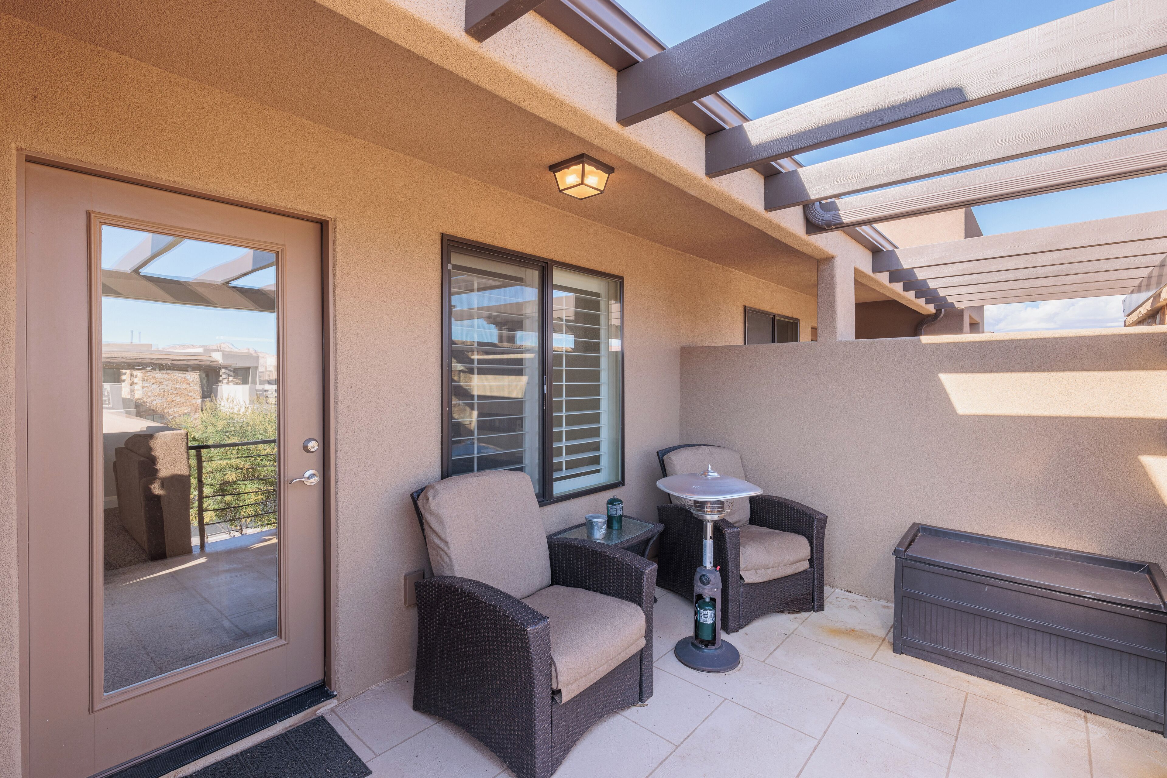 A balcony with wicker furniture, a small table, and a heater.