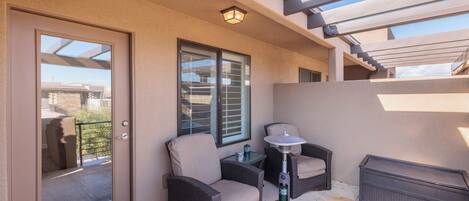 A balcony with wicker furniture, a small table, and a heater.