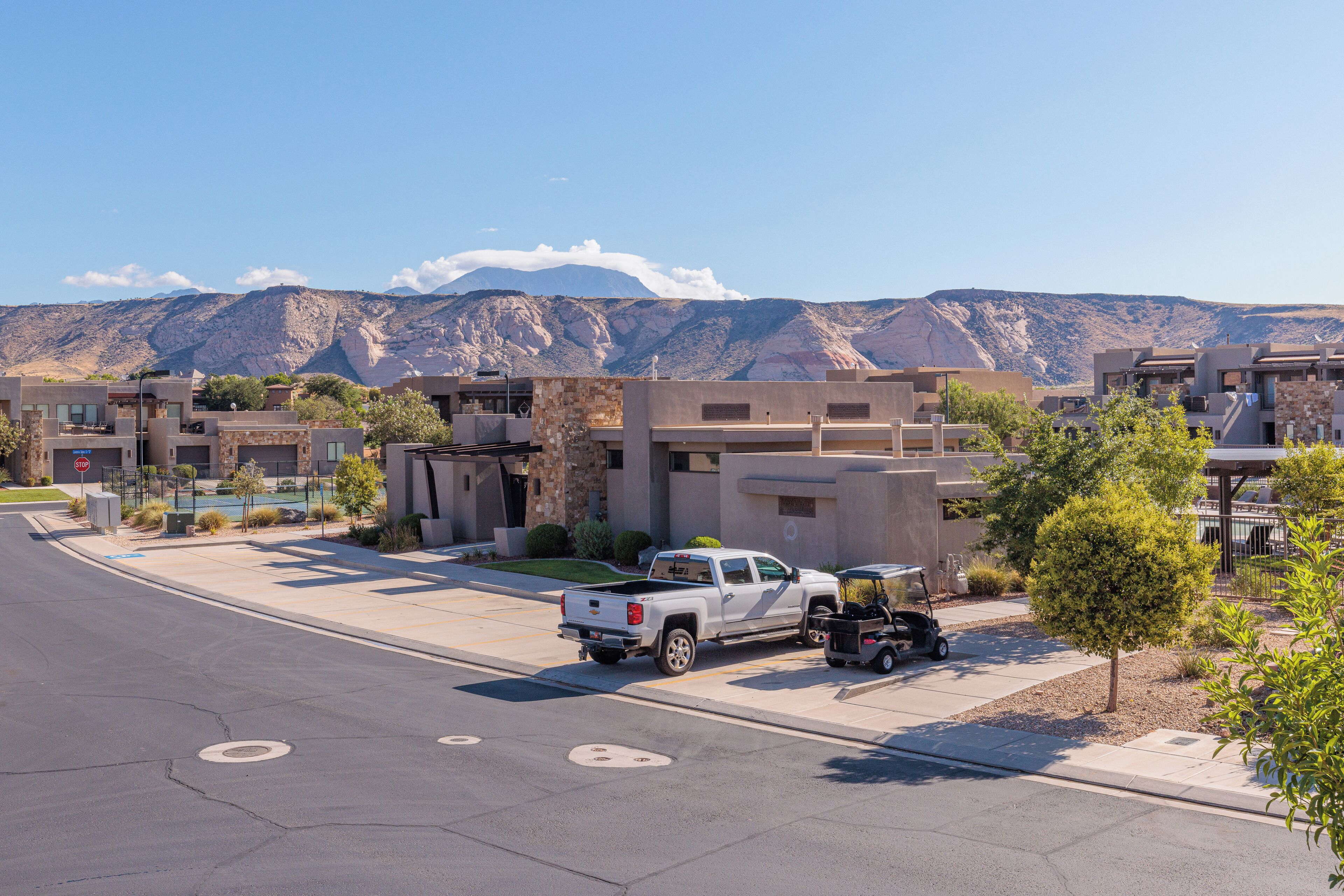 A residential street with modern houses, a white pickup truck, and a golf cart.