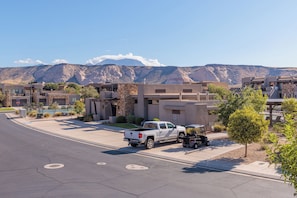 A residential street with modern houses, a white pickup truck, and a golf cart.