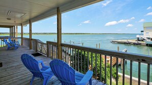 A covered deck with blue chairs and a view of the water. - Dream On #145 - Private boat dock, short walk to the beach, dog friendly! (Topsail Beach)