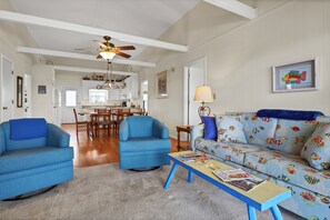 A living room with blue armchairs, a patterned sofa, and a wooden coffee table.
