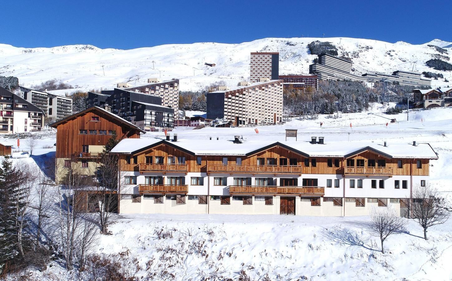 Ett hotell med flera v åningar, träbalkonger och en skidort som bakgrund.