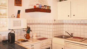 A compact kitchen with a microwave, stove, sink, and a small oven. There are cabinets, a spice rack, and a coffee maker on the counter.