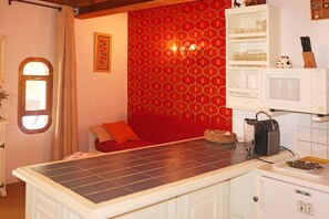 A kitchen with a red patterned wall, a white cabinet, and a tiled countertop. - Ski-in/ski-out & foot of the slopes, 3rd floor, view mountain, balcony, 30m², Les Orres (Les Orres)