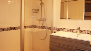 A modern bathroom with a glass-enclosed shower, a vanity with a sink, and a mirror above the vanity.
