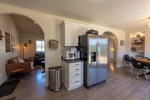 A modern kitchen with a stainless steel refrigerator, a microwave, and a dining area with a wooden table and chairs. - Beautiful Home, Fenced Yard, AC, Pet Friendly (Pagosa Springs)