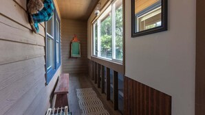 A narrow hallway with wooden walls, a bench, and a patterned rug.