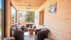A cozy wooden cabin with a wooden ceiling, a sofa set, a table, and a large window offering a view of the outdoors. - Chalet, wifi, 80m from ski slopes, terrace, parking, tv, ski locker, 300m², Les 2 Alpes (Les Deux Alpes)