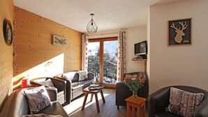 A cozy living room with a wooden wall, a sofa, a coffee table, and a television on a stand. - Chalet, wifi, 80m from ski slopes, terrace, parking, tv, ski locker, 300m², Les 2 Alpes (Les Deux Alpes)