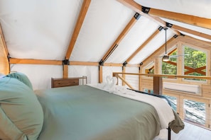 A tent-style room with a bed, wooden beams, a window, and a view of greenery. - Tree Farm Duo - Best of the Ozarks! (Walnut Shade)