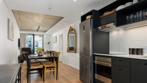 A modern kitchen with a stainless steel refrigerator, black cabinets, and a wooden dining table with chairs. - 529 Station House (Cape Town)