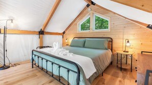 Un dormitorio acogedor con cama, una mesita, una lámpara de pie y una ventana.