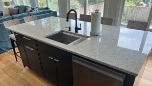 Eine Küche mit Granit-Arbeitsplatte, Spüle aus Edelstahl und Geschirrspüler.
