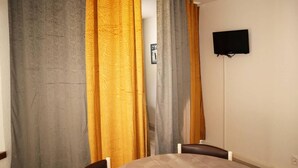 Une pièce comprenant une table ronde, deux chaises et un téléviseur à écran plat fixé au mur.