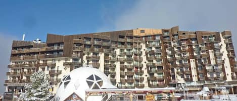 A multi-story hotel with balconies and a large white dome structure in the foreground.