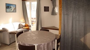 Un salon confortable avec un canapé, une table ronde et une vue sur l’extérieur par une fenêtre.