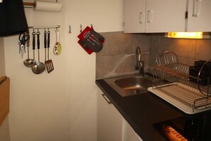 A kitchen with a sink, a utensil rack, and a dish drying rack.