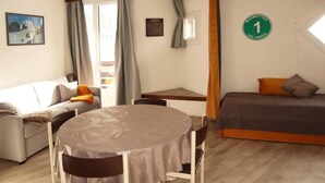 Une pièce confortable avec un lit, un canapé, une table à manger et une petite fenêtre.