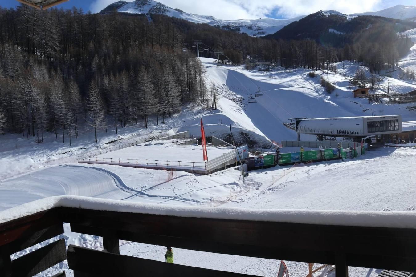 A ski resort with a chairlift, a ski lift station, and a snow-covered mountain backdrop.