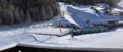 A ski resort with a chairlift, a ski lift station, and a snow-covered mountain backdrop.