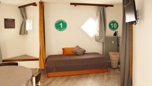 Une petite pièce agréable, avec un lit, une table et une chaise. Deux panneaux sur le mur indiquent les numéros de chambre : 1 et 10.