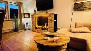 Una sala de estar moderna con chimenea, un sofá, una mesa de centro y un televisor montado en la pared.