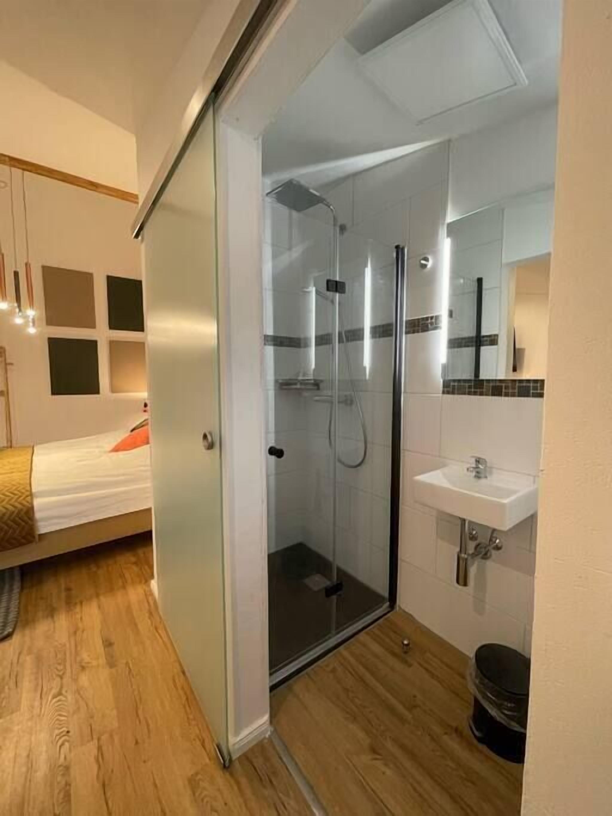 Un baño moderno con cabina de ducha de vidrio, lavamanos y espejo.