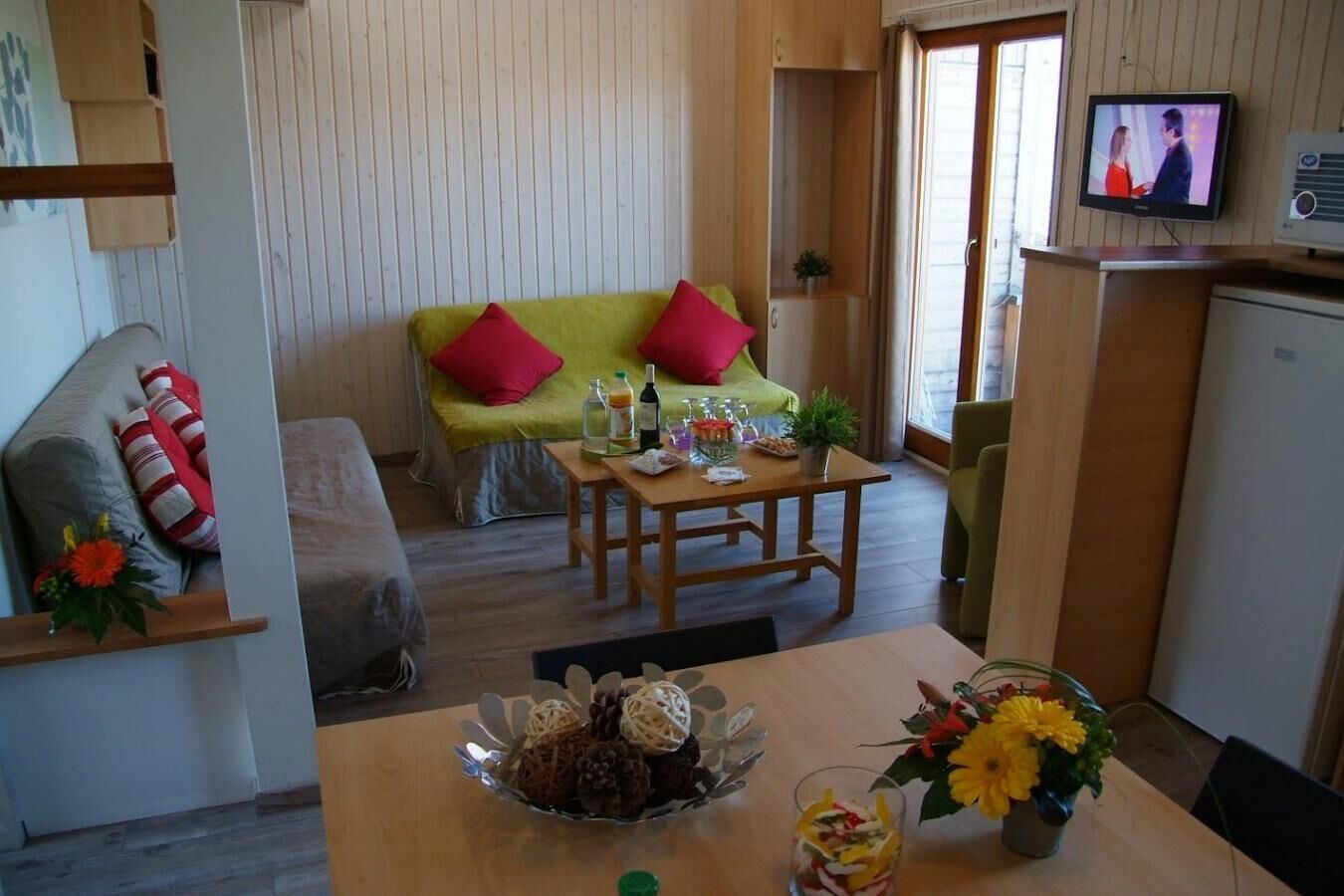 Un salon chaleureux avec un canapé vert, une table basse en bois et un téléviseur posé sur un meuble.