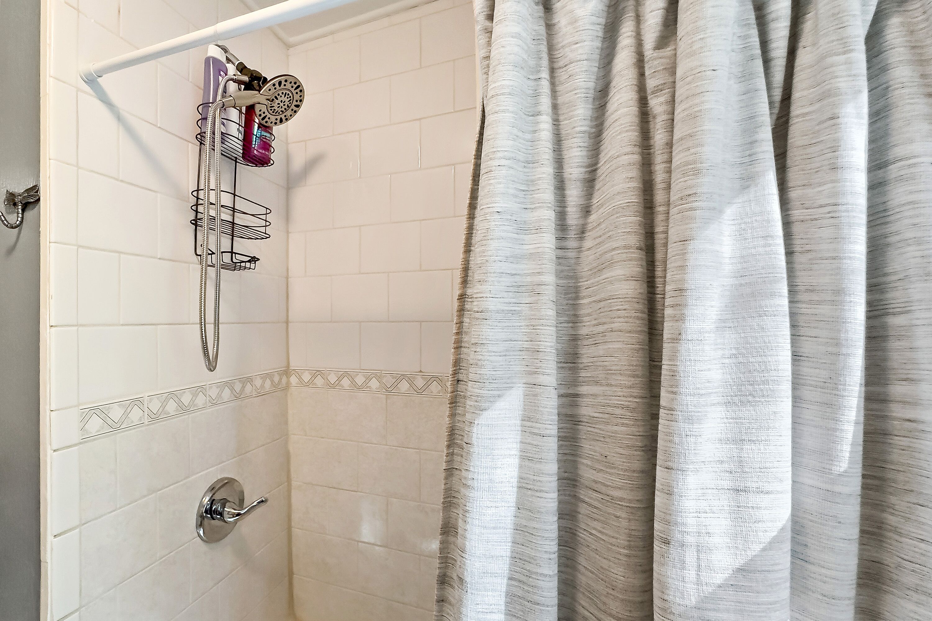 Ducha con cabezal de ducha de mano, grifo empotrado en la pared y esquinero.